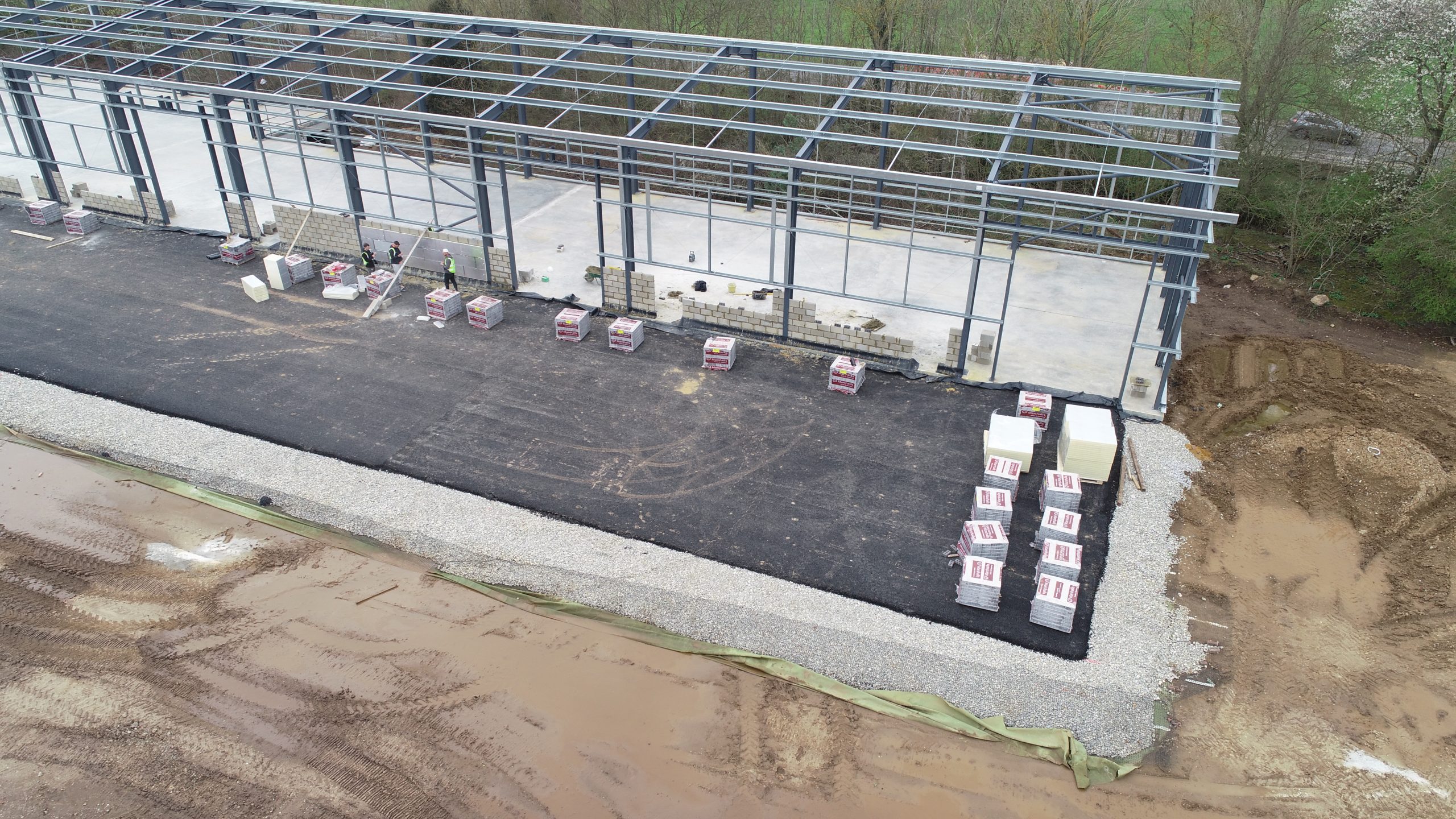 frame for steel building with contractors adding bricks